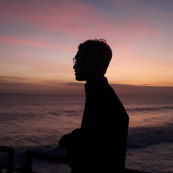 Silhouette of a person meditating against a vibrant sunrise.